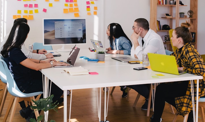 five person by table watching turned on white iMac