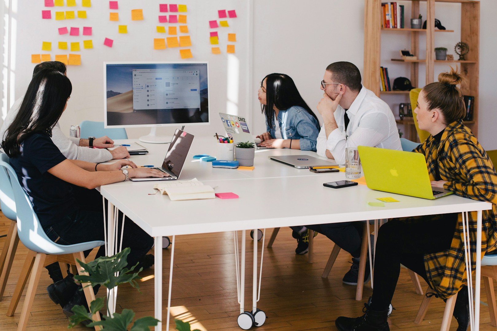 Photo of 5 people around a table looking at information on a monitor