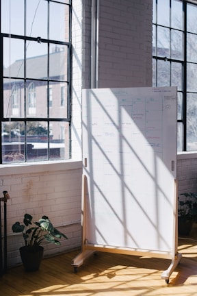 A bright room with sunlight streaming in, showing a whiteboard full of plans and doodles.