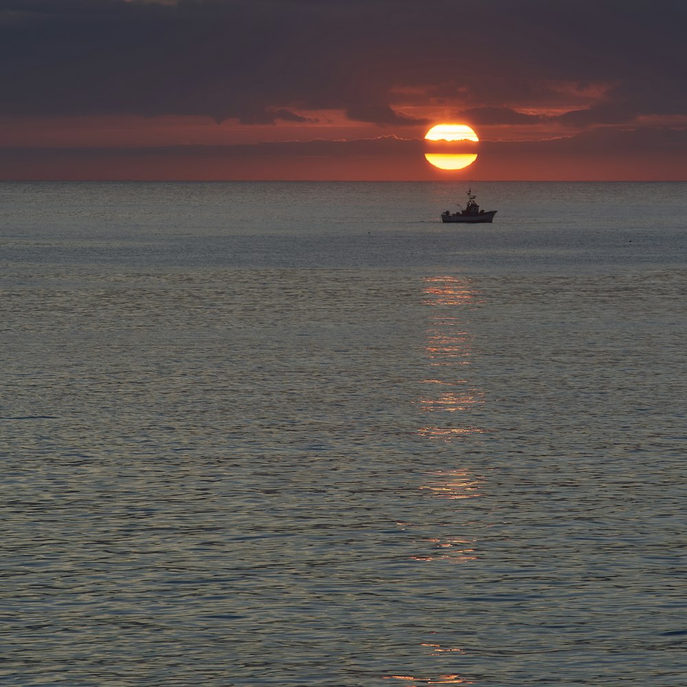 boat sailing on calm sea during sunset