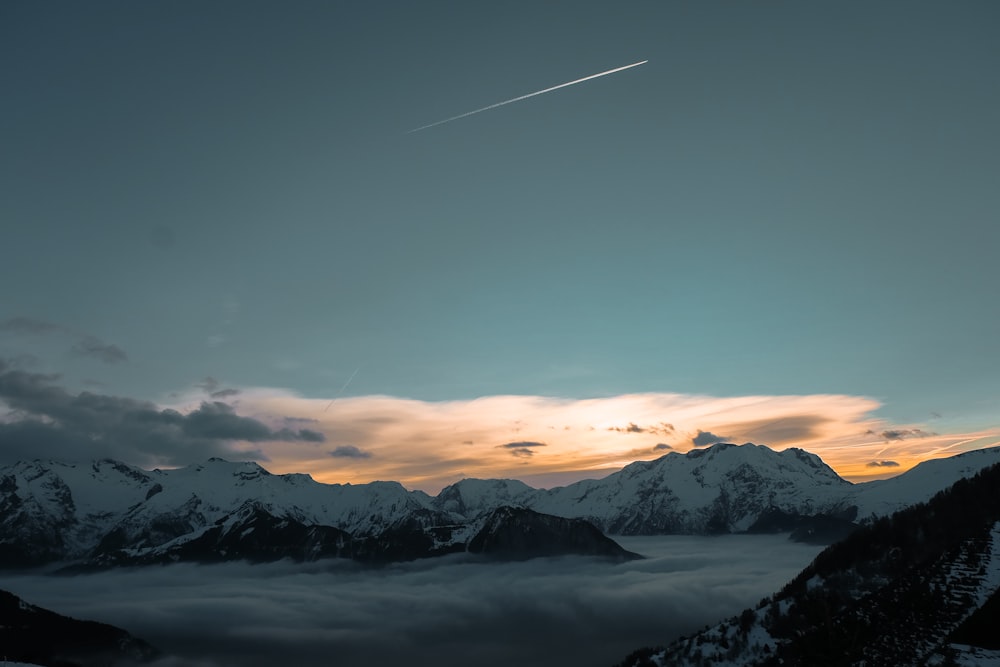 shooting star above snow-capped mountains during golden hour
