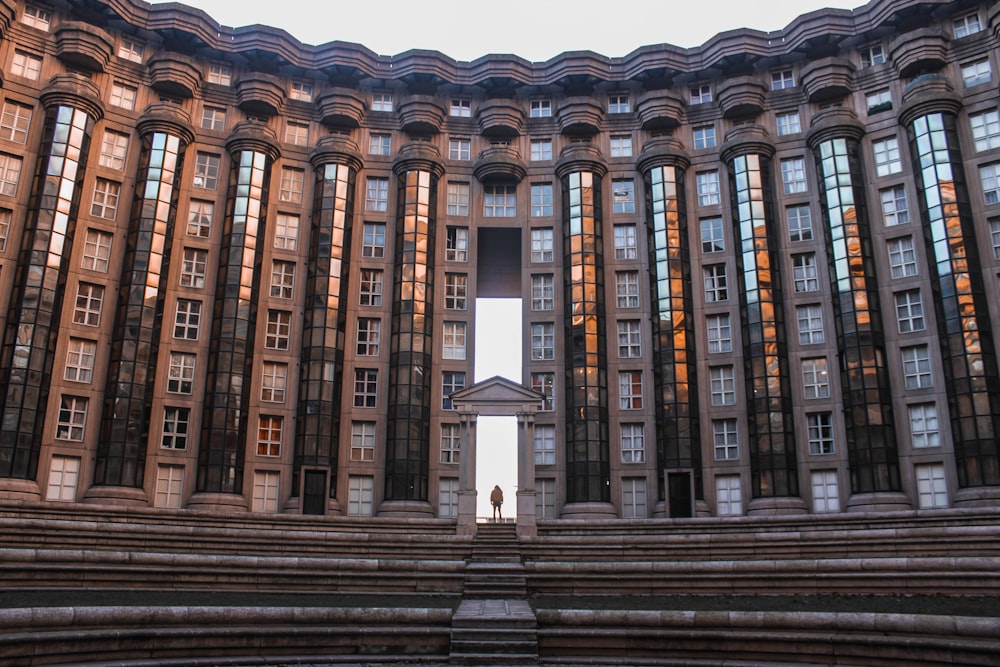 person standing between hallway of concrete building during daytime