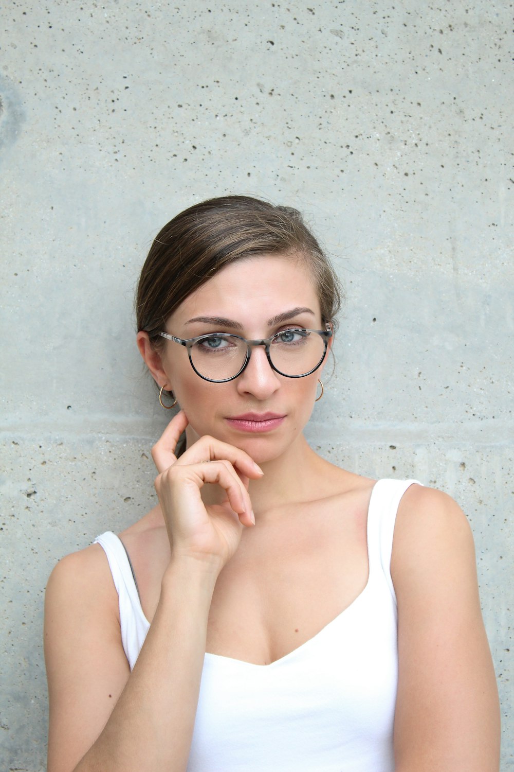 woman in white tank top touching her cheek