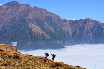 Women hiking up a mountain path with panoramic views in the background.