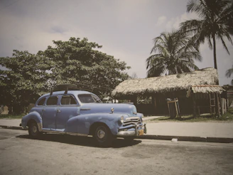 A cozy car parked by lush green rice terraces under a bright blue sky in Ubud.