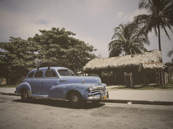 A cozy car parked by lush green rice terraces under a bright blue sky in Ubud.