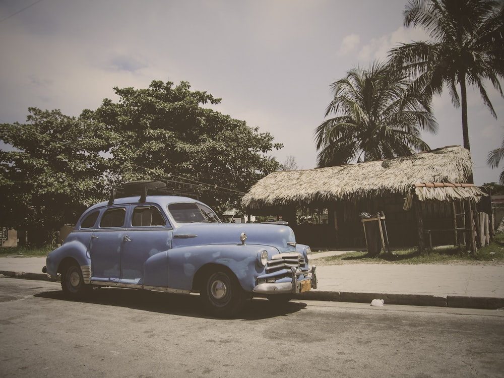 vintage blue car parked near brown house