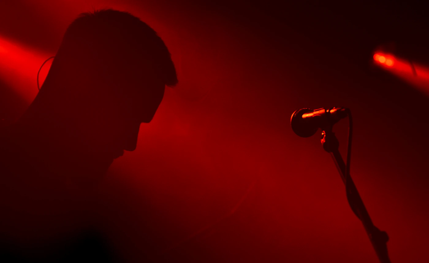 Singer at a microphone under red stage light