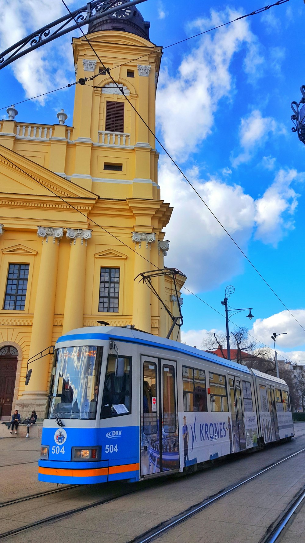 blue and white bus near yellow building