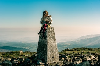 a learner sitting on top of a remote stone pillar