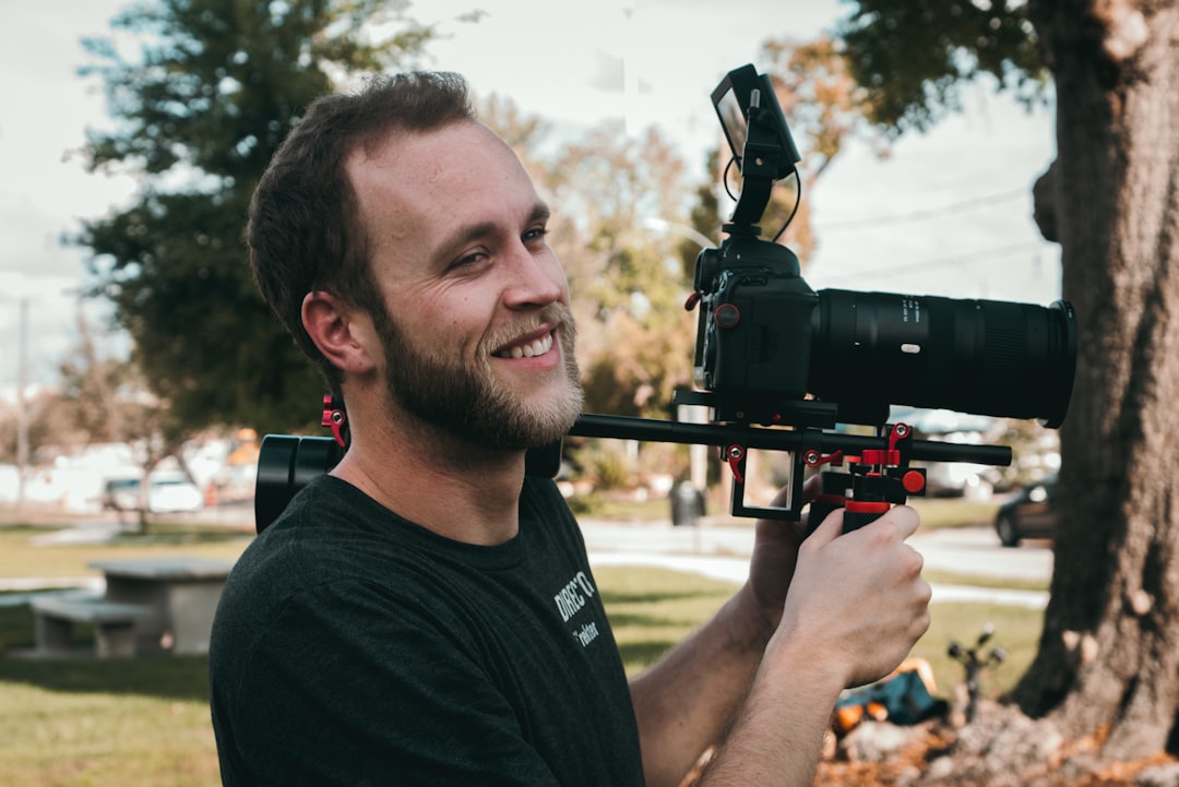 man smiling standing near the DSLR camera,