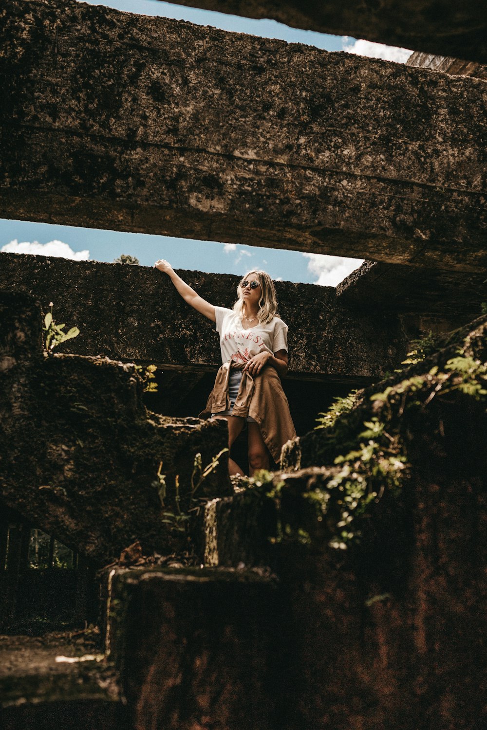 a woman in a white shirt and brown skirt standing on a rock formation