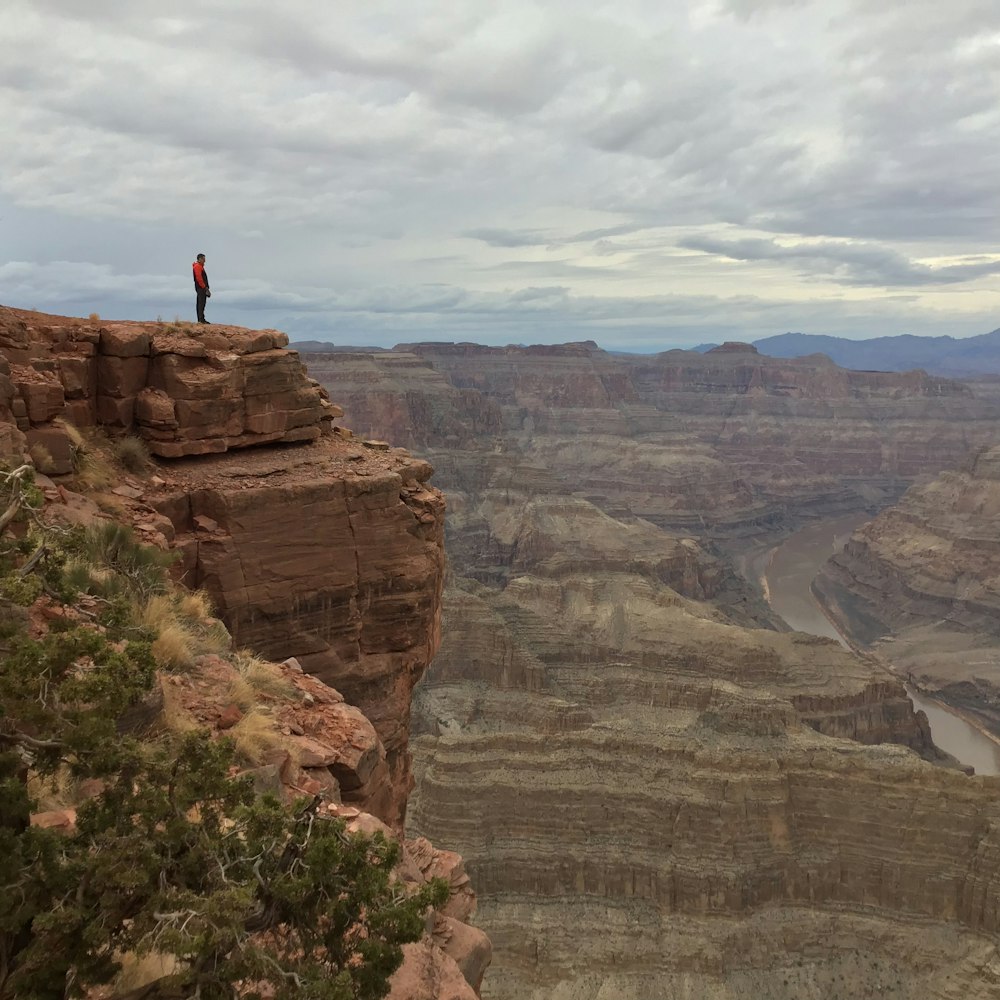 person standing near edge of rocky mountain