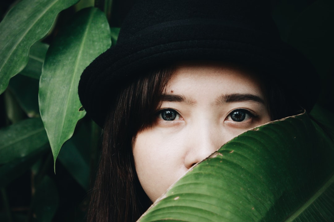 woman hides behind broad green leaf
