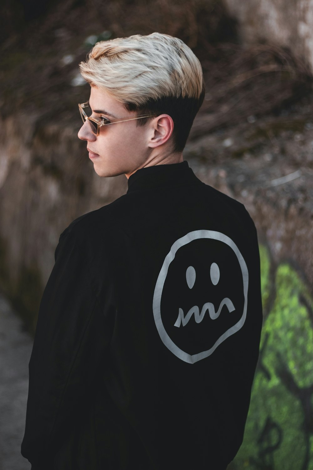 man in sunglasses and black jacket near rock