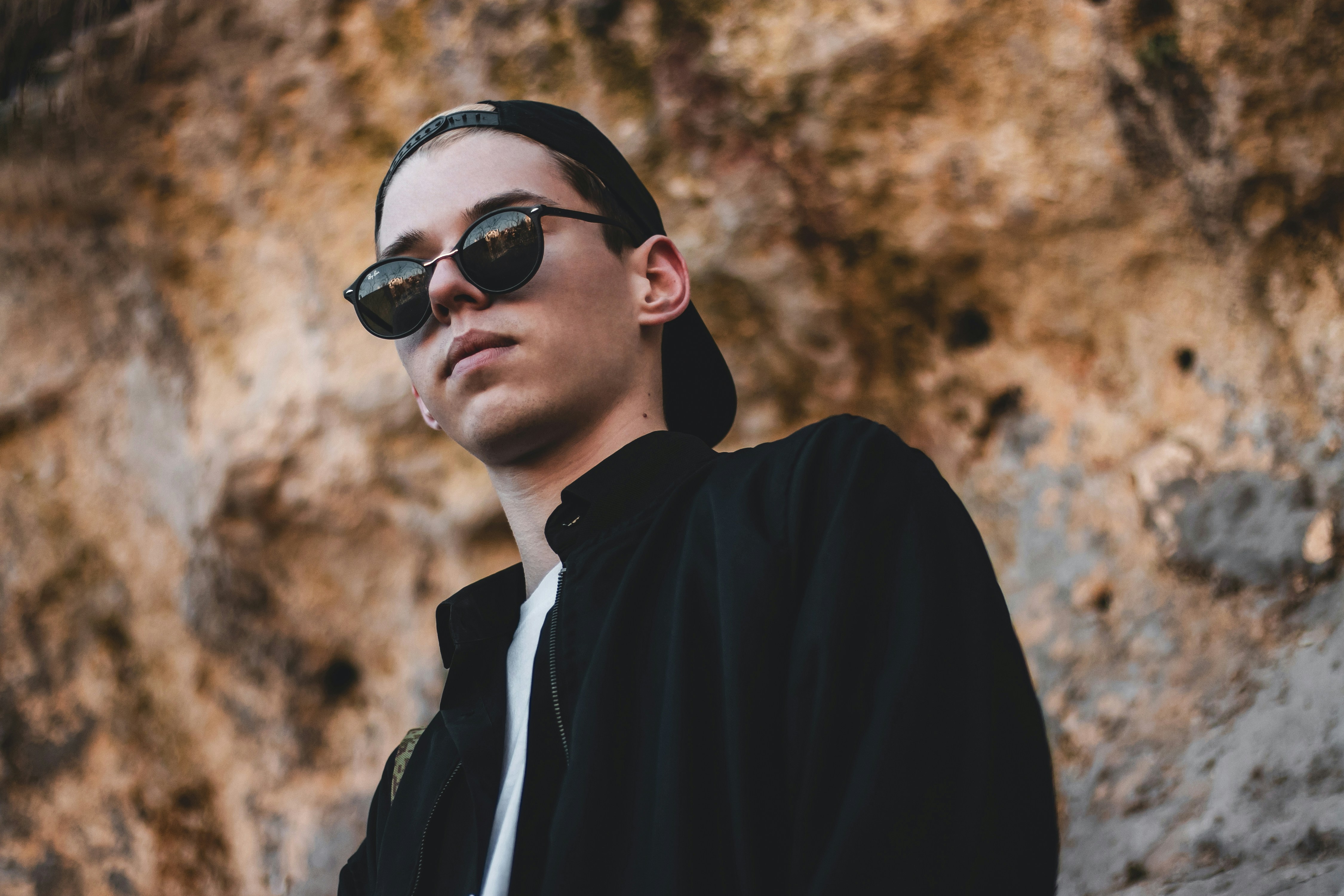 man in black framed sunglasses near brown rock