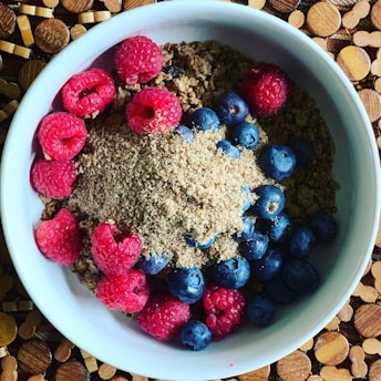 A vibrant single-serving breakfast bowl with fresh berries and granola on a clean white plate.