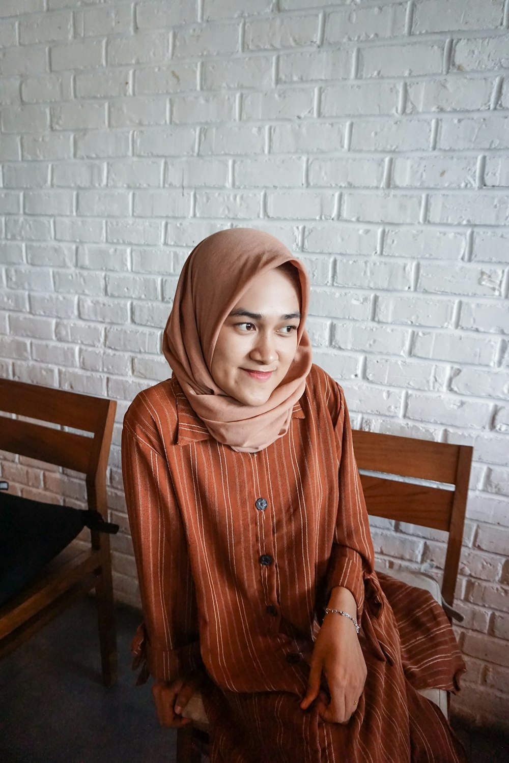 woman in brown abaya dress sitting on chair and smiling