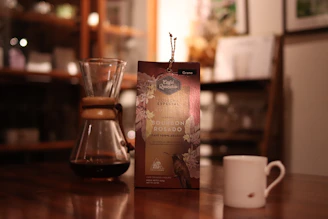 A cozy kitchen scene with a box of Three Floyds brewed coffee and a steaming cup beside it.