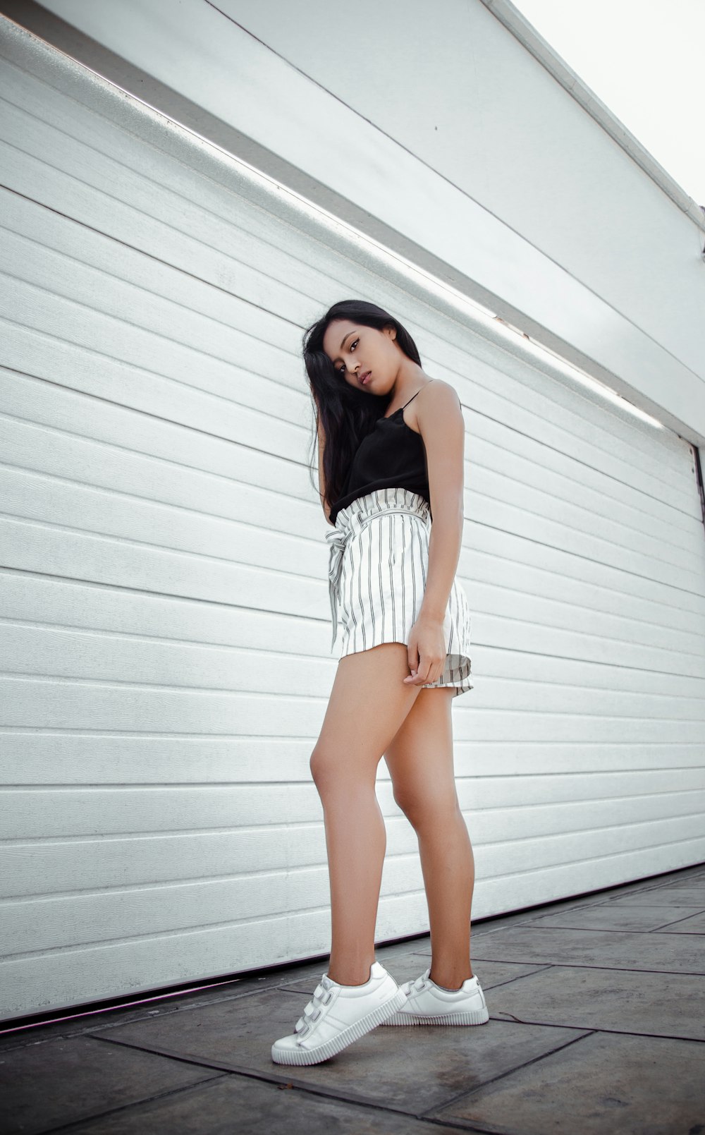 woman in a black tank top and white striped shorts