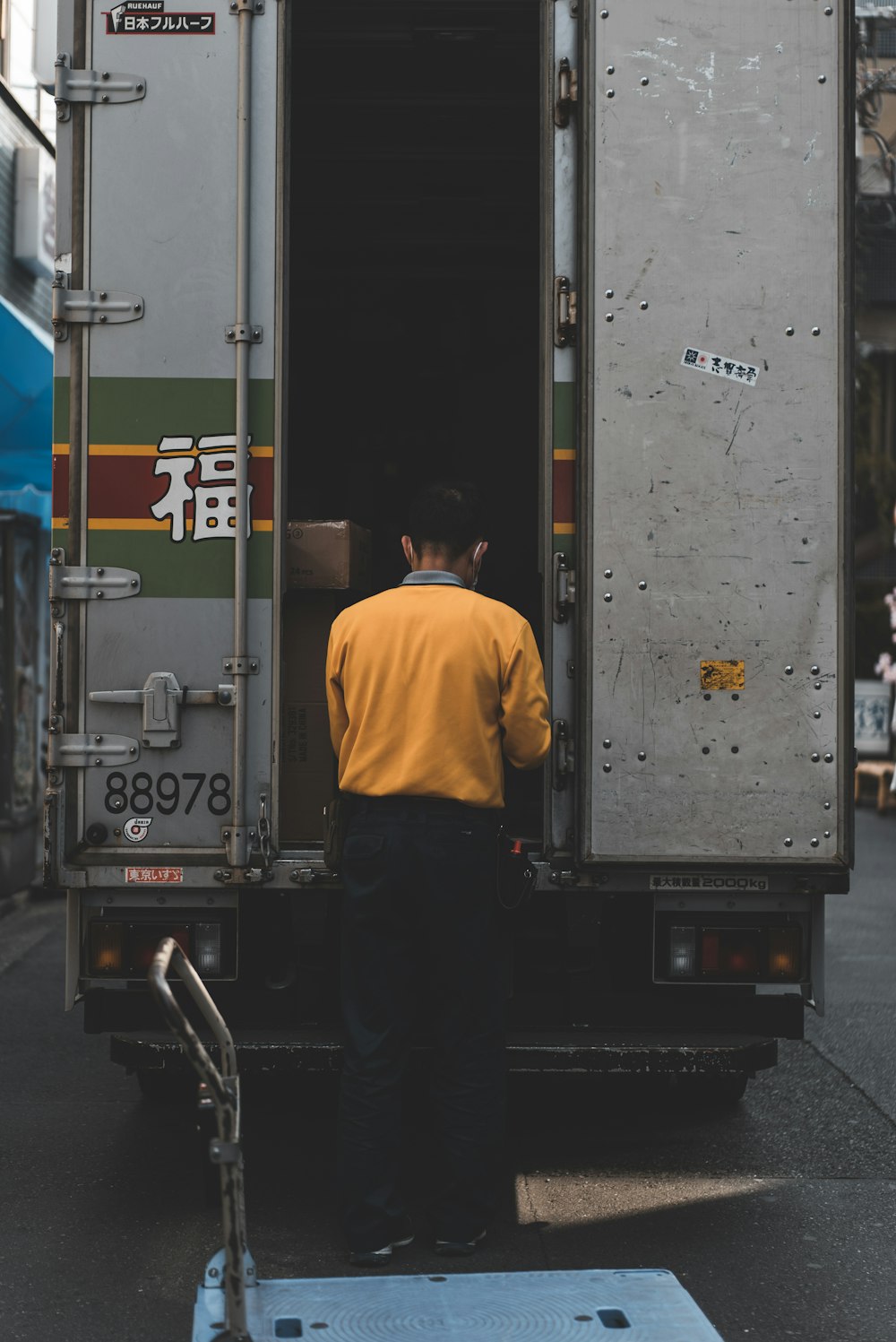 man in yellow sweater behind gray box truck