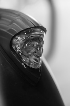 Close-up of the custom 3D-printed helmet chin mount securely attached to a sleek motorcycle helmet, highlighting its contoured base and aerodynamic arm.