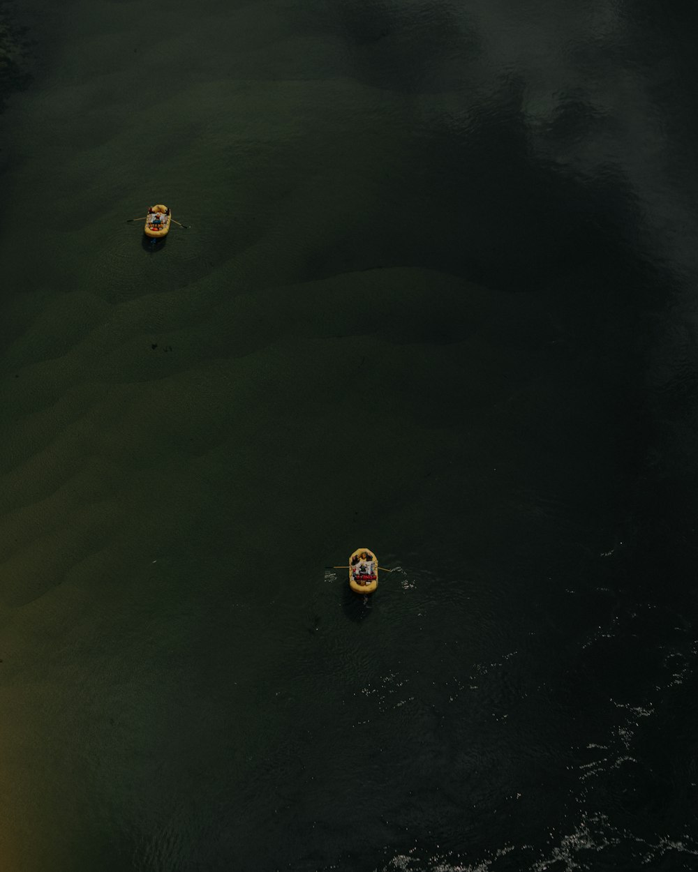 two yellow boats on body of water