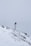 A snow-covered mountainous landscape with a metal pole topped by a small solar panel or device. A red and white windsock hangs from the pole, indicating wind direction. The surroundings are enveloped in fog, creating a serene and isolated atmosphere.