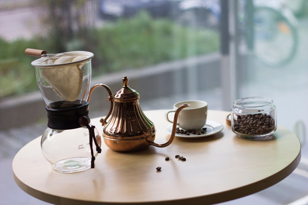 brass-colored steel teapot on white table