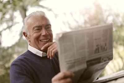 A happy retired person smiling while reviewing a bank statement showing returned funds.