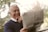 An elderly man smiling while reading a blog on a tablet.