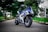 Electric motorcycles parked in an urban setting with green trees in the background.