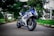 Electric motorcycles parked in an urban setting with green trees in the background.