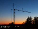 Evening view of a concrete pump boom silhouetted against the sky at a site in the Federal District.