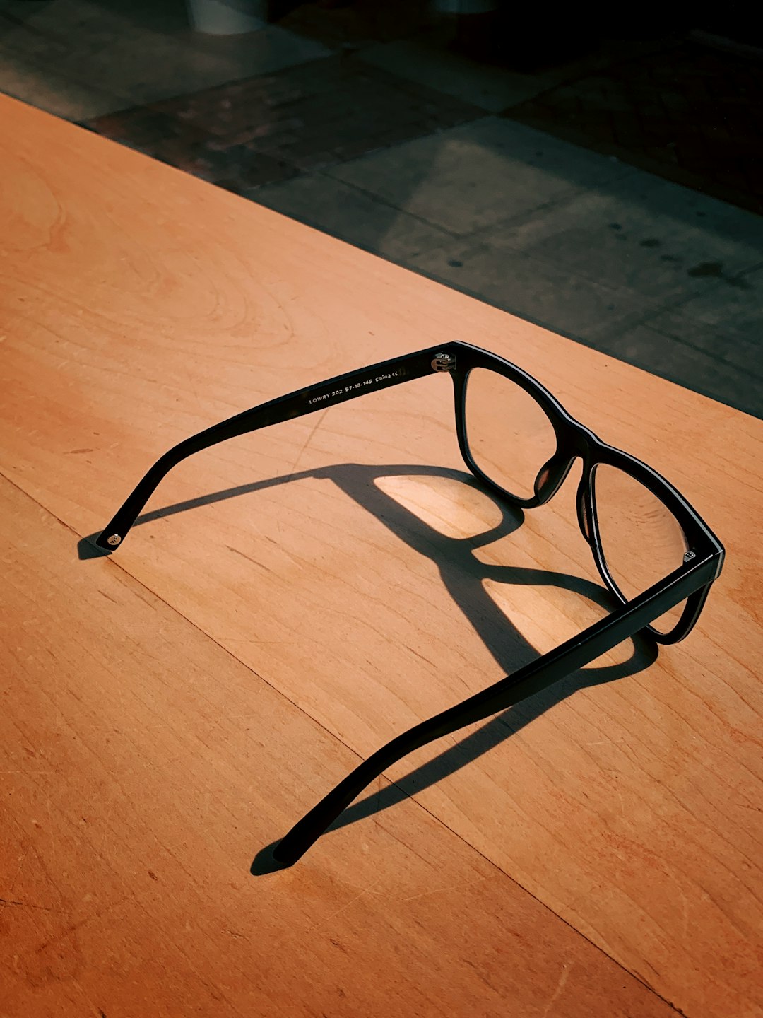 black framed eyeglasses on brown surface