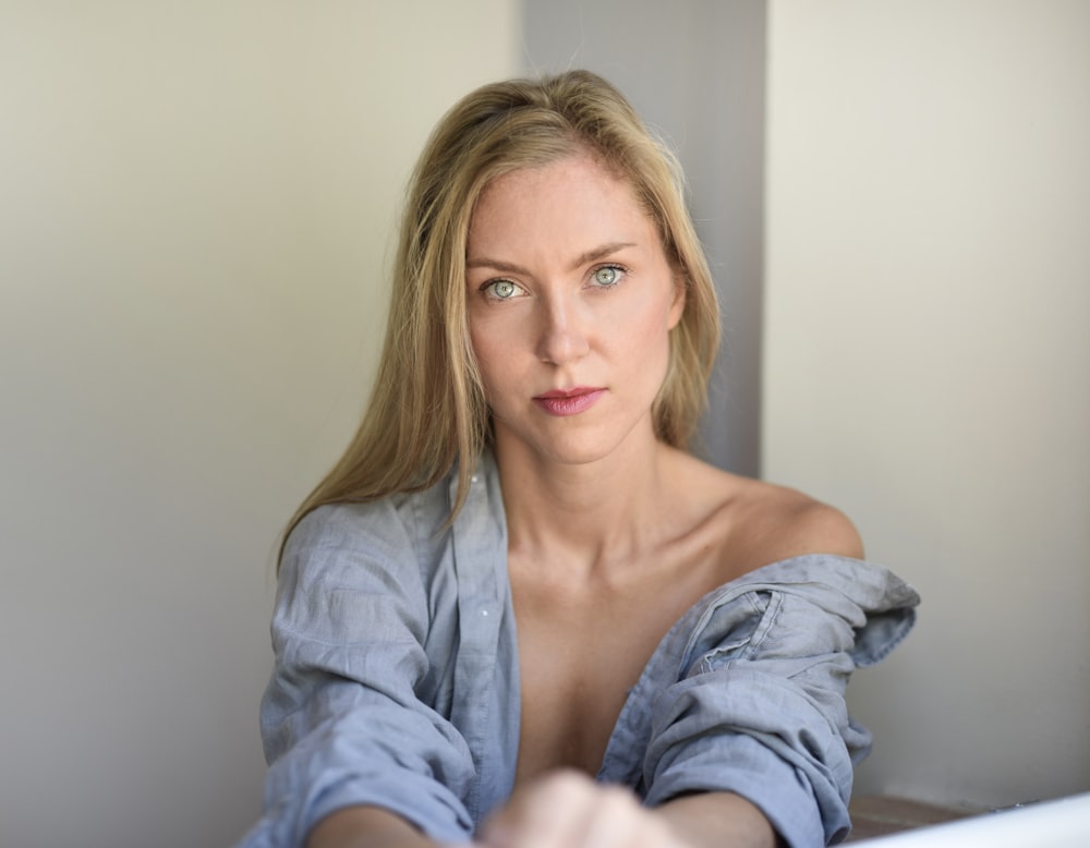 woman wearing blue button-up long-sleeved shirt near white surface