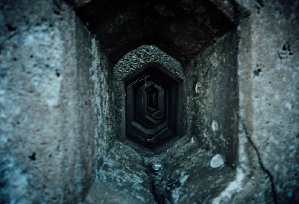 a tunnel in a stone wall with a light at the end