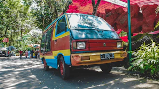 A vibrant photo of a colorful van parked in a rural village, children eagerly picking books from its shelves.
