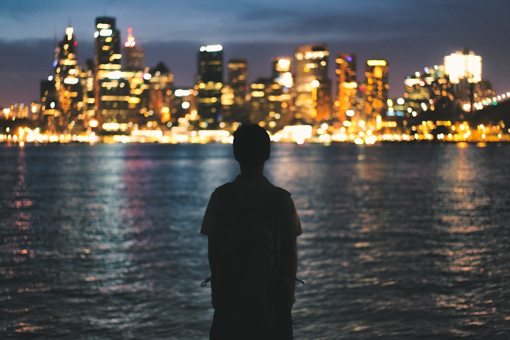 silhouette of person standing near light buildings