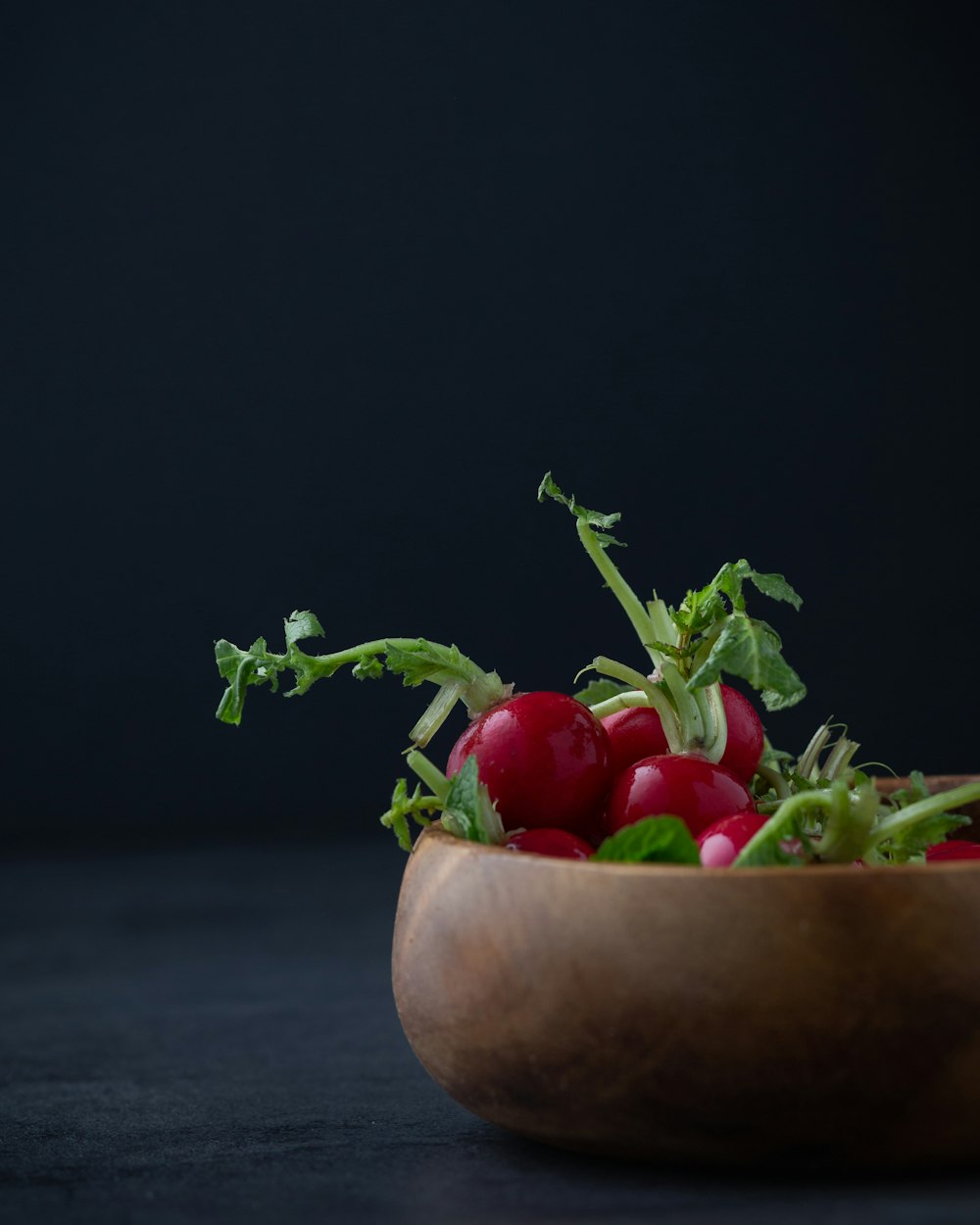 tomates rojos en un cuenco redondo de madera marrón