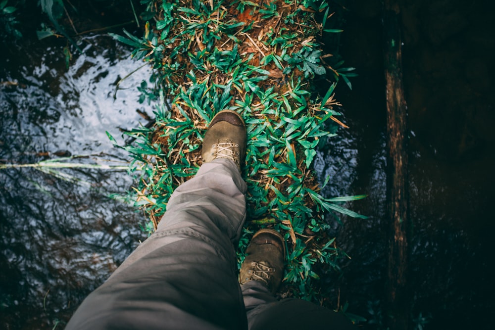 person wearing brown pants walking on green grass