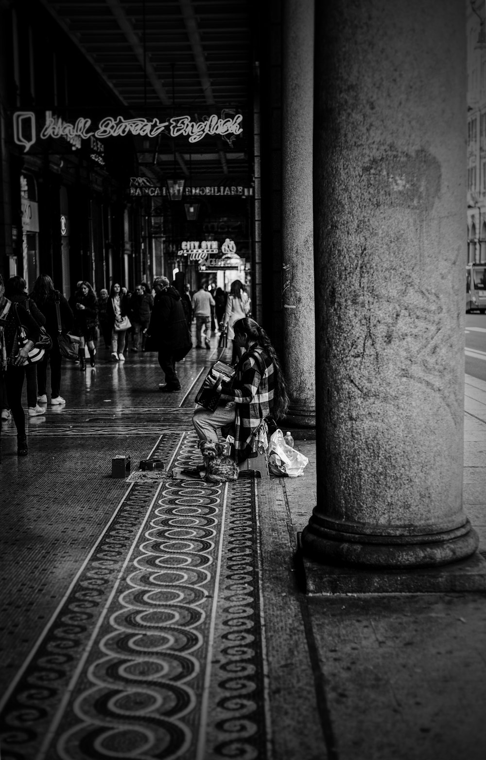 una persona seduta a terra accanto a un pilastro