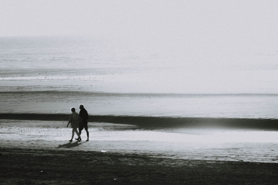 two person walking on seashore