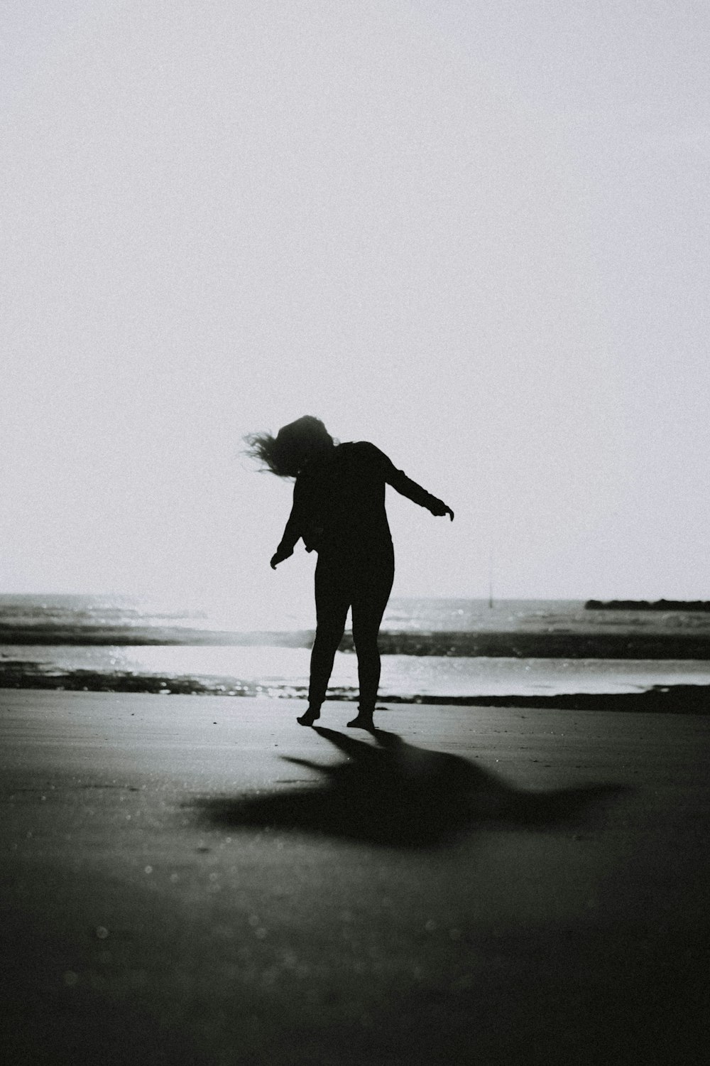 grayscale photo of woman waving her hair on shore