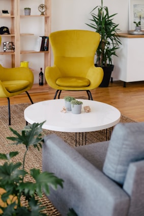 two mustard-colored chairs chairs beside round white wooden coffee table