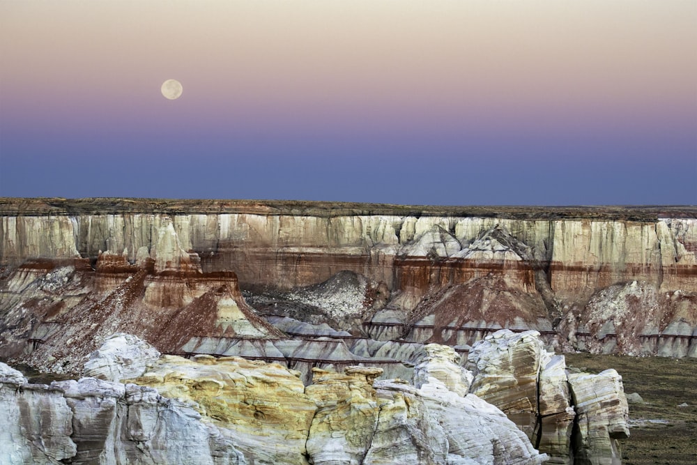 canyon under clear sky with visible moon at daytime