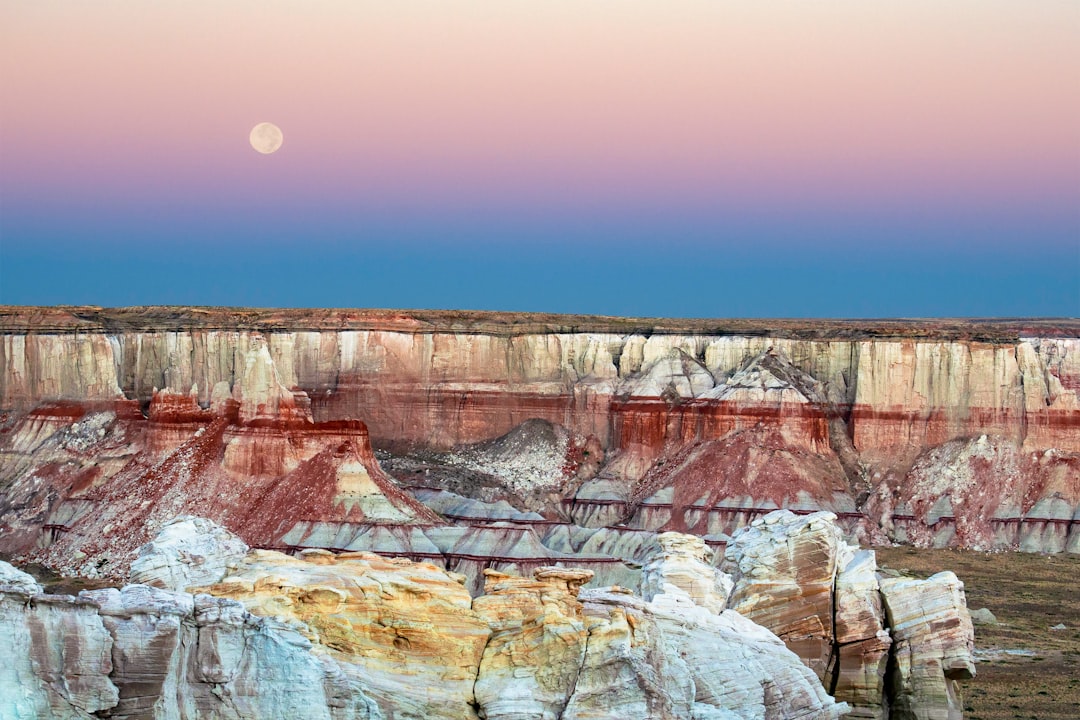 canyon under clear sky with visible moon at daytime