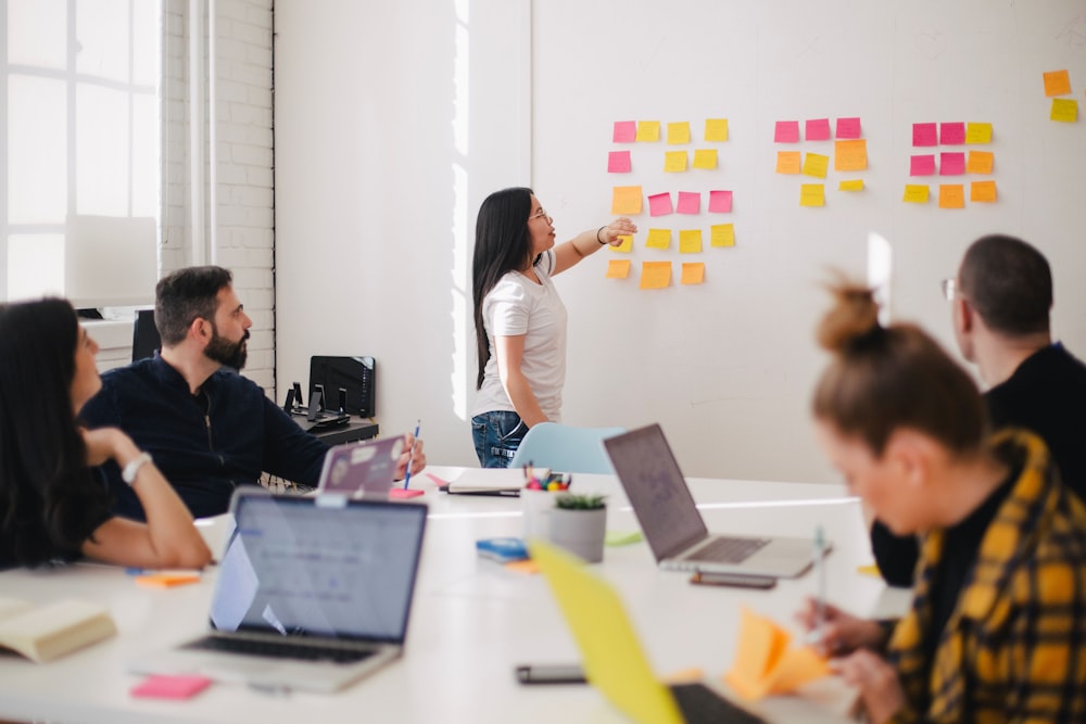 A woman placing sticky notes on a whiteboard