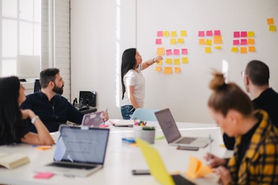 woman placing sticky notes on wall collaboration teams background