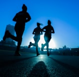 silhouette of three women running on grey concrete road